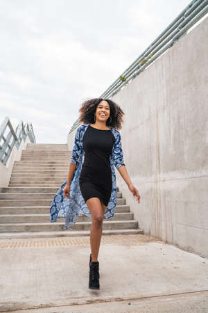 Portrait of young confident afro american woman walking on stairs outdoors.