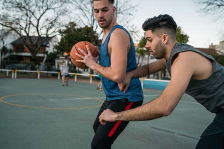 Young basketball players playing one-on-one on outdoor court. Sport and basketball concept.の写真素材