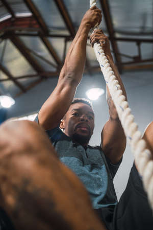 Portrait of an athletic man doing climbing exercise at the gym. Crossfit, sport and healthy lifestyle concept.の写真素材