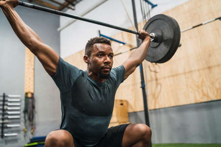 Portrait of young crossfit athlete doing exercise with a barbell. Crossfit, sport and healthy lifestyle concept.の写真素材