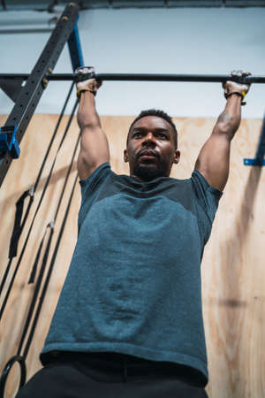 Portrait of an athletic man doing pull up exercise at the gym. Sport and healthy lifestyle concept.