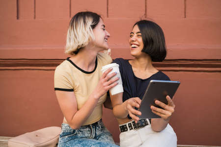 Portrait of lovely lesbian couple spending time together and taking selfie with digital tablet...