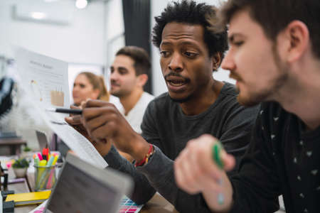 Two creative designers working in a project together and sharing new ideas on workplace. Business...