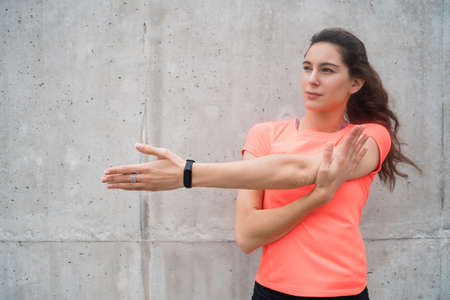 Portrait of an athletic woman stretching her arms before exercise outdoors. Sport and healthy...