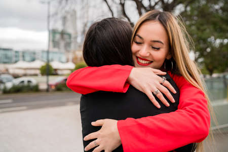 Portrait of two young friends hugging each other outdoors at the street. Lifestyle and friendship concept.の写真素材