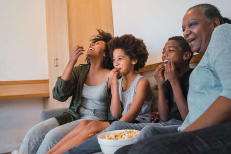 Grandmother, mother and children watching a movie at home.の写真素材