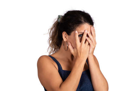 Young woman looking shy hiding behind her hand.