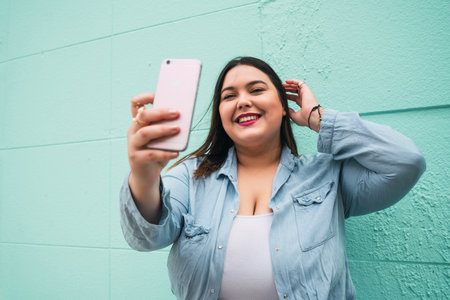 Young plus size woman taking selfies with phone.の写真素材