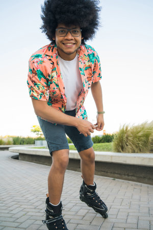 Young Latin man rollerskating outdoors.