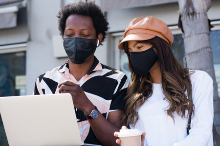 Young couple using laptop outdoors.