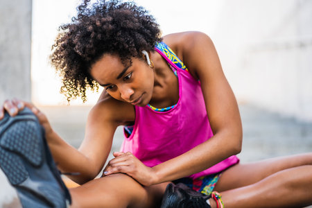 Afro athlete woman stretching legs before exercise.の写真素材