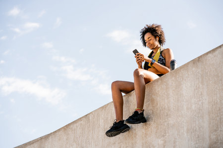 Athlete woman using her mobile phone outdoors.