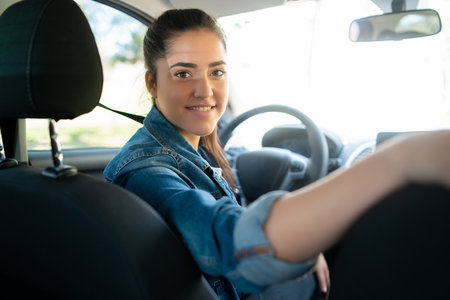 Woman driving her car and looking at back seatの写真素材