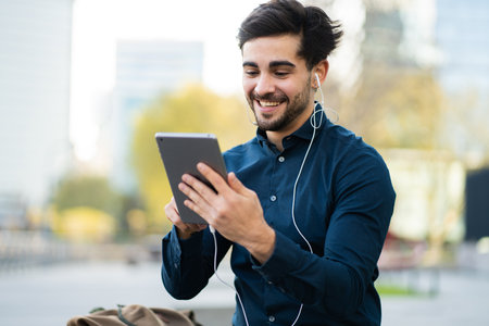 Young man having a video call on digital tablet outdoors.の写真素材