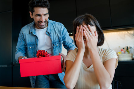 Man surprising his girlfriend with a gift.の写真素材