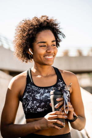 Afro athlete woman holding a bottle of water.