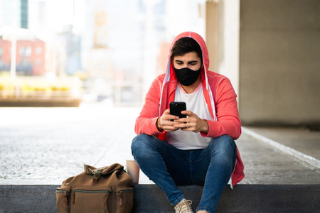 Young man using his mobile phone outdoors.の写真素材