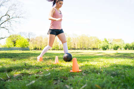 Young female soccer player practicing on field.