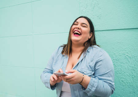 Young plus size woman using her mobile phone.の写真素材