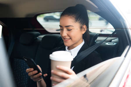 Businesswoman using mobile phone in car.