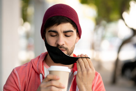 Young man drinking a cup of coffee outdoors.の写真素材