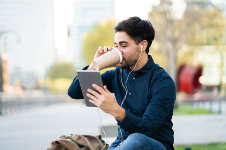 Young man having a video call on digital tablet outdoors.の写真素材