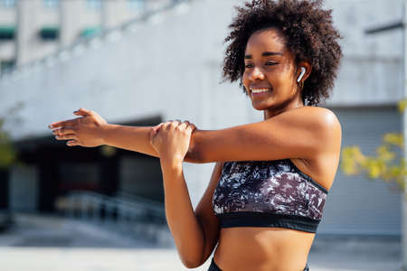 Afro athletic woman stretching arms before exercise.