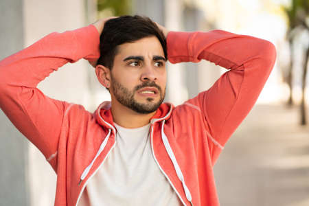 Young man looking stressed and worried outdoors.