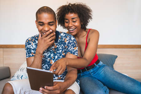 Young latin couple using digital tablet at home.