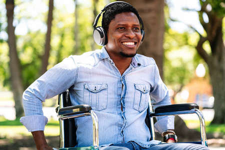 Man in wheelchair listening music with headphones.
