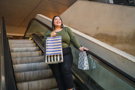 Young woman holding shopping bags at mall.