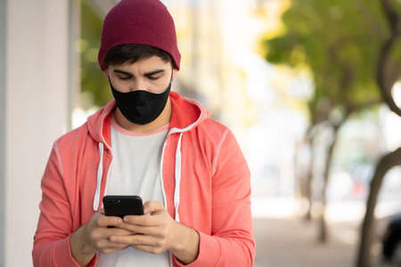 Young man using his mobile phone outdoors.の写真素材