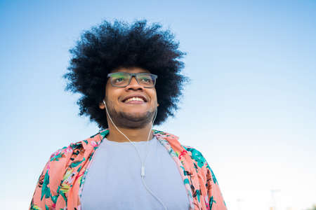 Latin man listening music with earphones outdoors.の写真素材