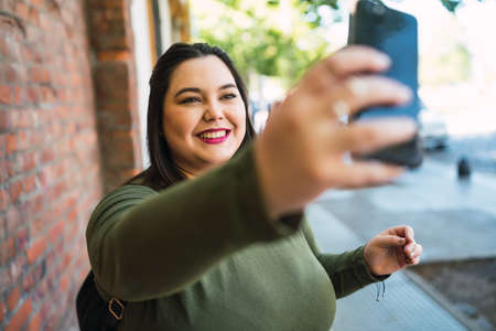 Young plus size woman taking selfies with phone.の写真素材