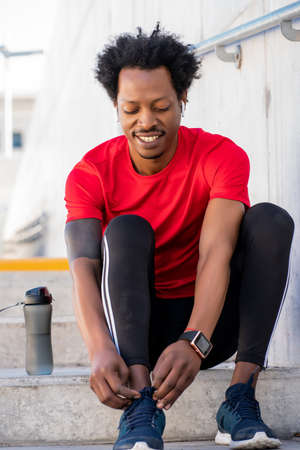 Afro athletic man tying his shoelaces.の写真素材