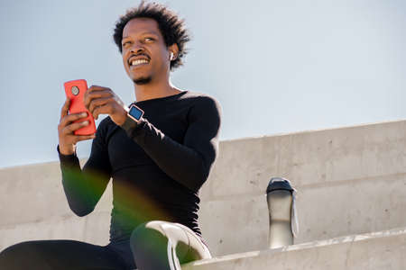 Athletic man using his mobile phone outdoors.の写真素材