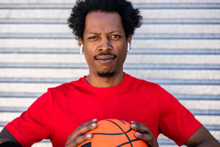 Afro athlete man holding a basketball ball outdoors.の写真素材