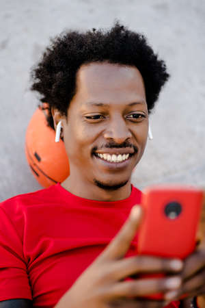 Athletic man using his mobile phone outdoors.の写真素材