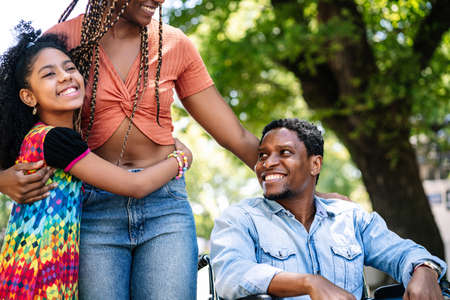 Man in a wheelchair enjoying a walk outdoors with family.の写真素材