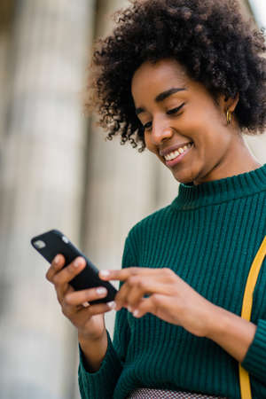 Business woman using her mobile phone outdoors.の写真素材