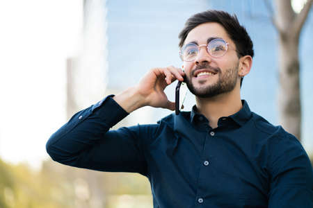 Young man talking on the phone outdoors.の写真素材