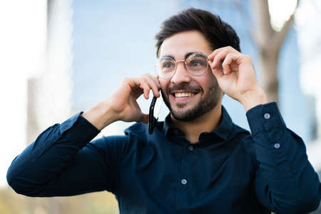 Young man talking on the phone outdoors.の写真素材