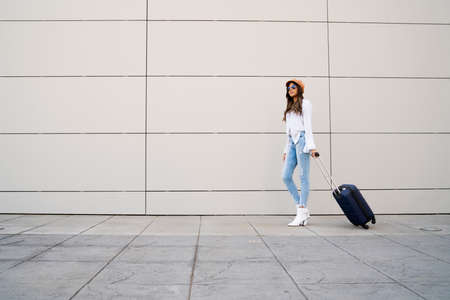 Young woman carrying a suitcase outdoors.の写真素材