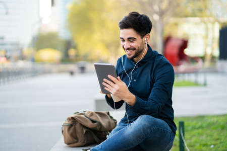 Young man having a video call on digital tablet outdoors.の写真素材