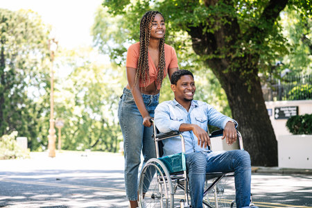 Man in a wheelchair enjoying a walk with his girlfriend.の写真素材