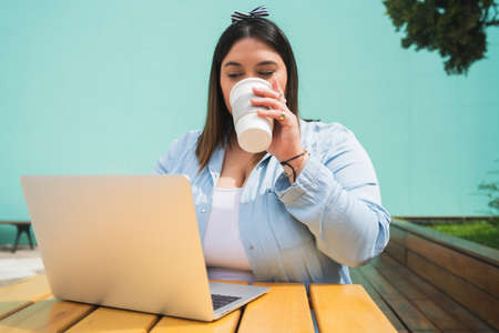 Young plus size woman using laptop at coffee shop.