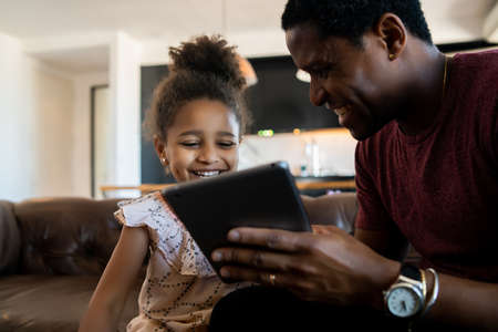 Father and daughter using digital tablet at home.の写真素材