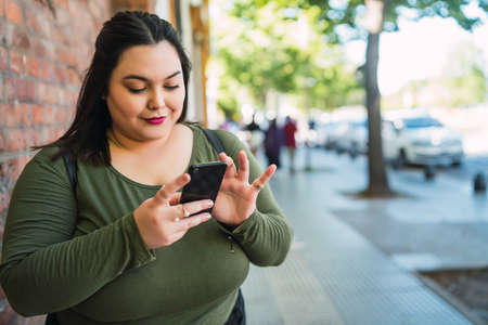 Young plus size woman using her mobile phone.の写真素材