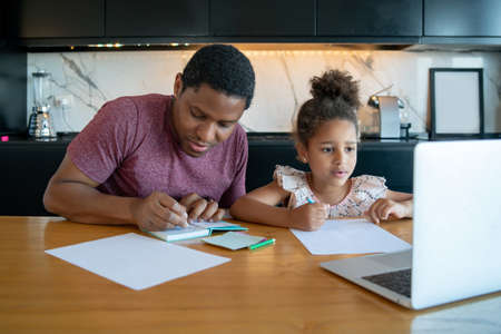 A father helping his daughter with homeschool.の写真素材