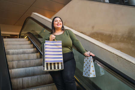 Young woman holding shopping bags at mall.の写真素材